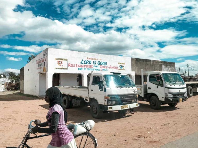 This photo, published in January, 2020 portrays a woman from Mangochi, Malawi riding her bike past men in trucks depicting the divide and common differences experienced between men and women in the informal sector. Credit: Aditya Septiansya