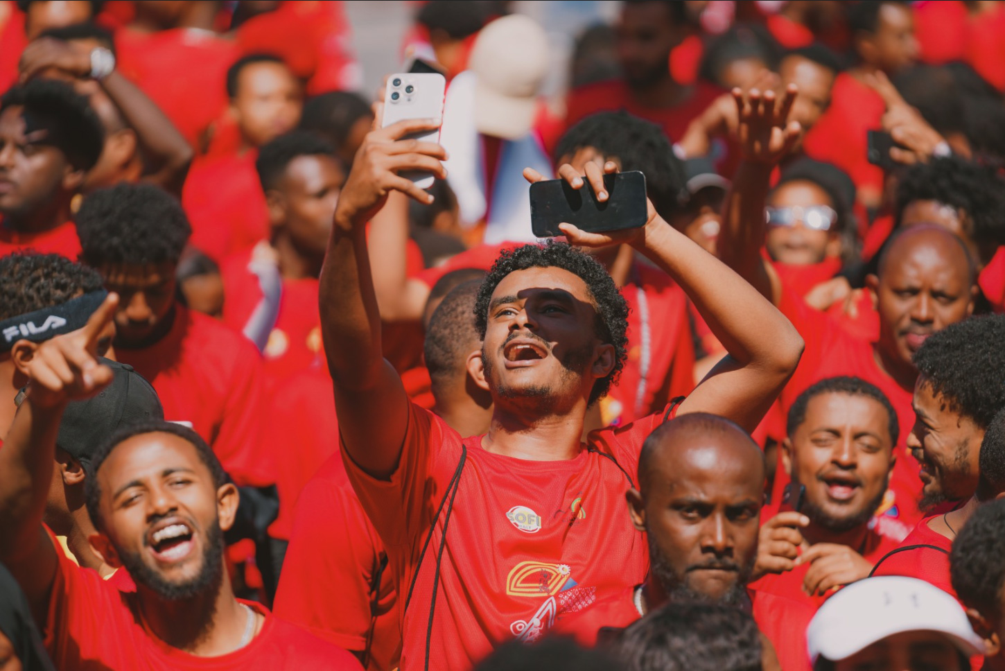 Cover Photograph: Abel Alemseged, “Joyful crowd of adults dressed in red holding smartphones, celebrating outdoors during the day,” Pexels, 2021.